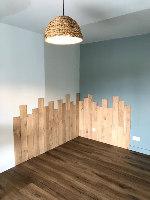 Tête de lit en planches de bois découpées, mur bleu-gris