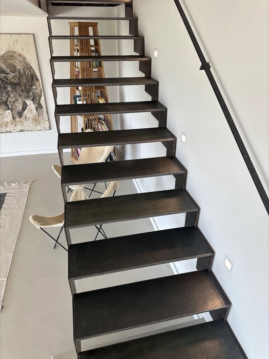 Escalier suspendu aux marches habillées de bois foncé