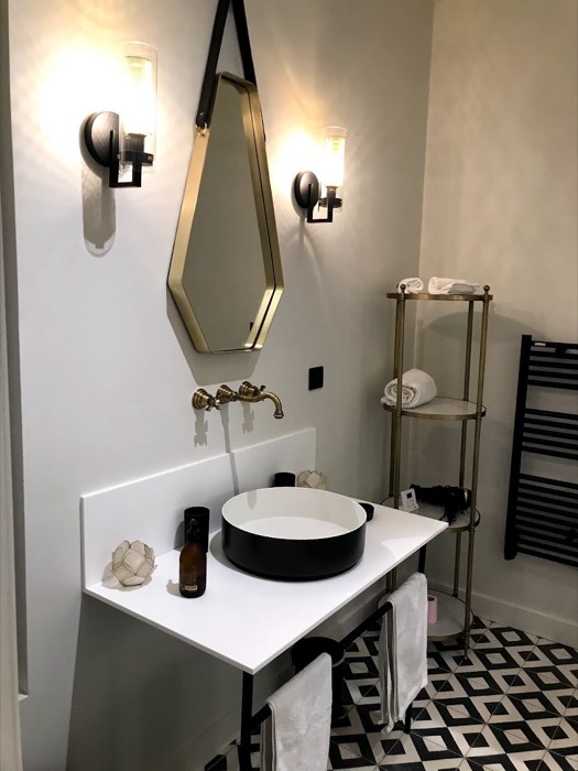 Vasque noire à poser, miroir hexagonal et sol en carreaux ciment géométriques